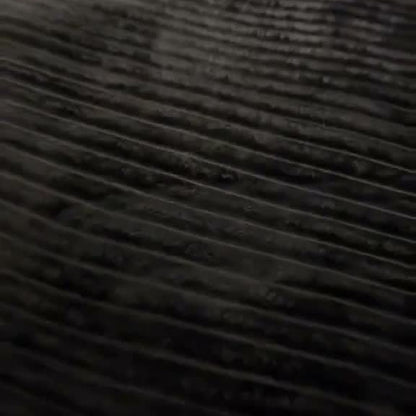 The Charcoal ribbed-stripe plush blanket on a bed