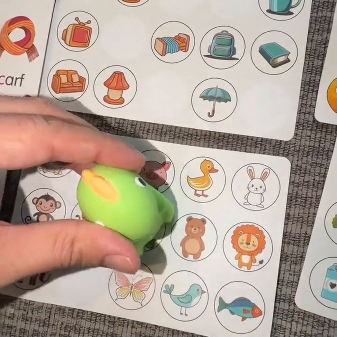 The green dinosaur reader beside illustrated cards and learning sticker sheets on a couch.