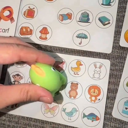 The green dinosaur reader beside illustrated cards and learning sticker sheets on a couch.