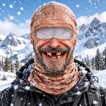 The Uncle mask worn in the snow: bald, stubble beard, wide gap-toothed grin, mountains behind.