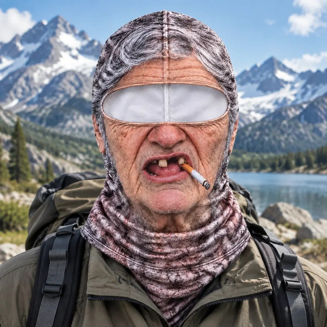 The Grandma mask worn on a hike: grey hair, gap teeth, a cigarette, a mountain lake behind.