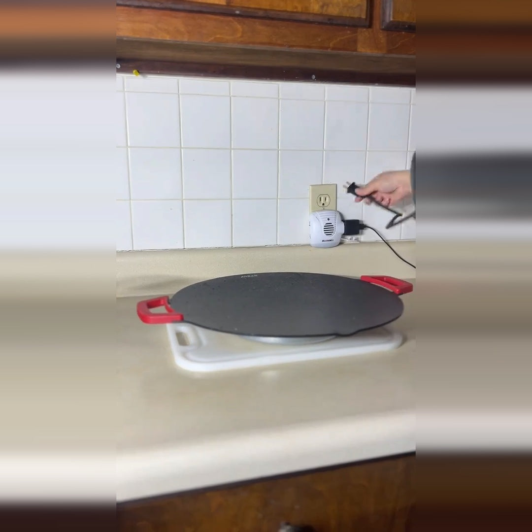 The real round SizzleMate electric grill with red side handles on a kitchen counter