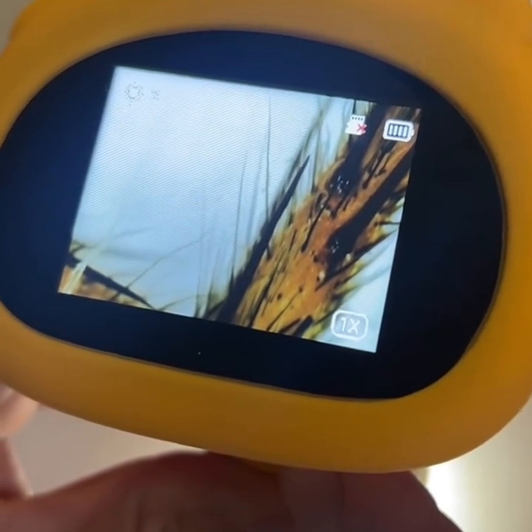 Two hands hold the yellow scope; its screen shows a grass macro. Crop square below the video caption.