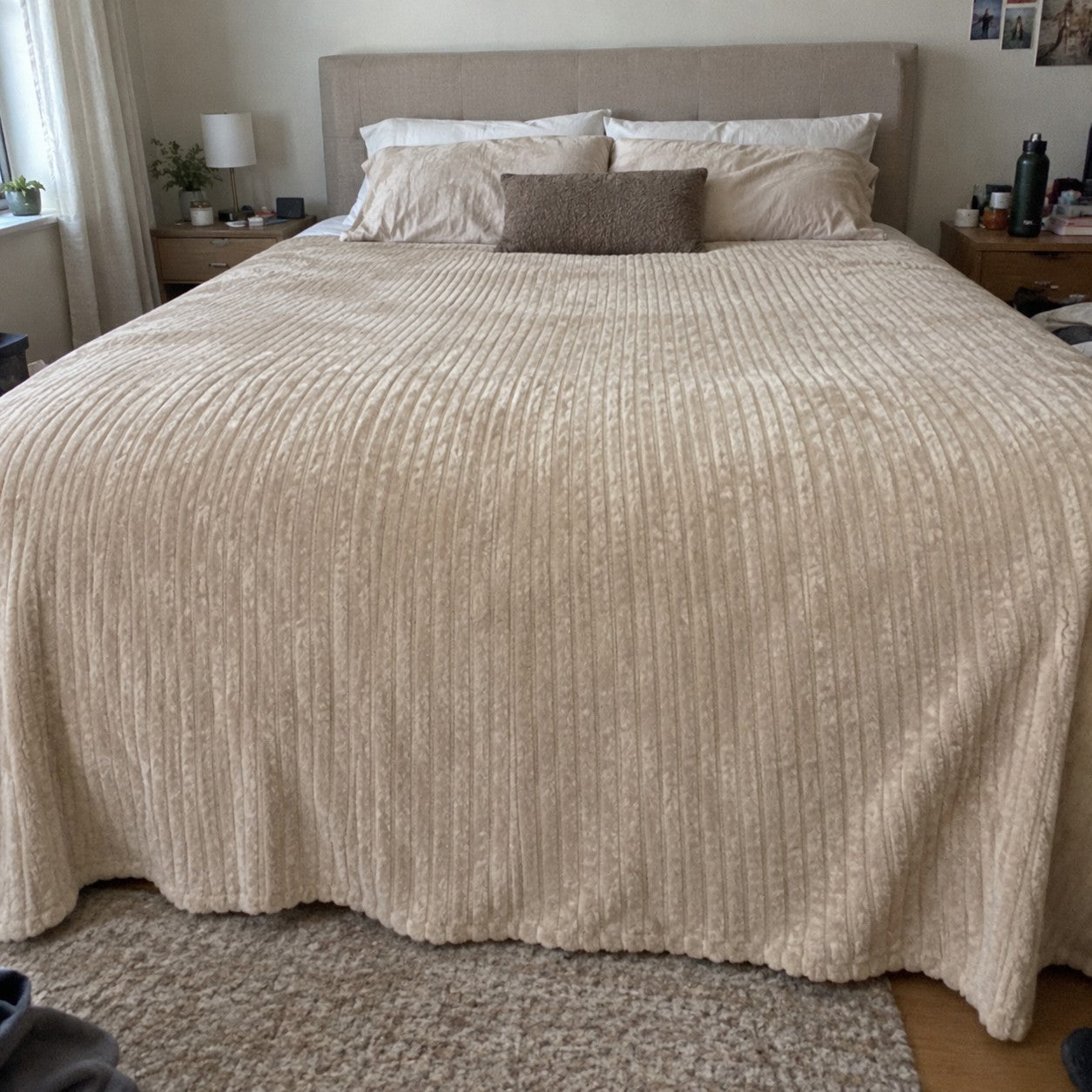 Cream blanket draping past the sides of a made king bed