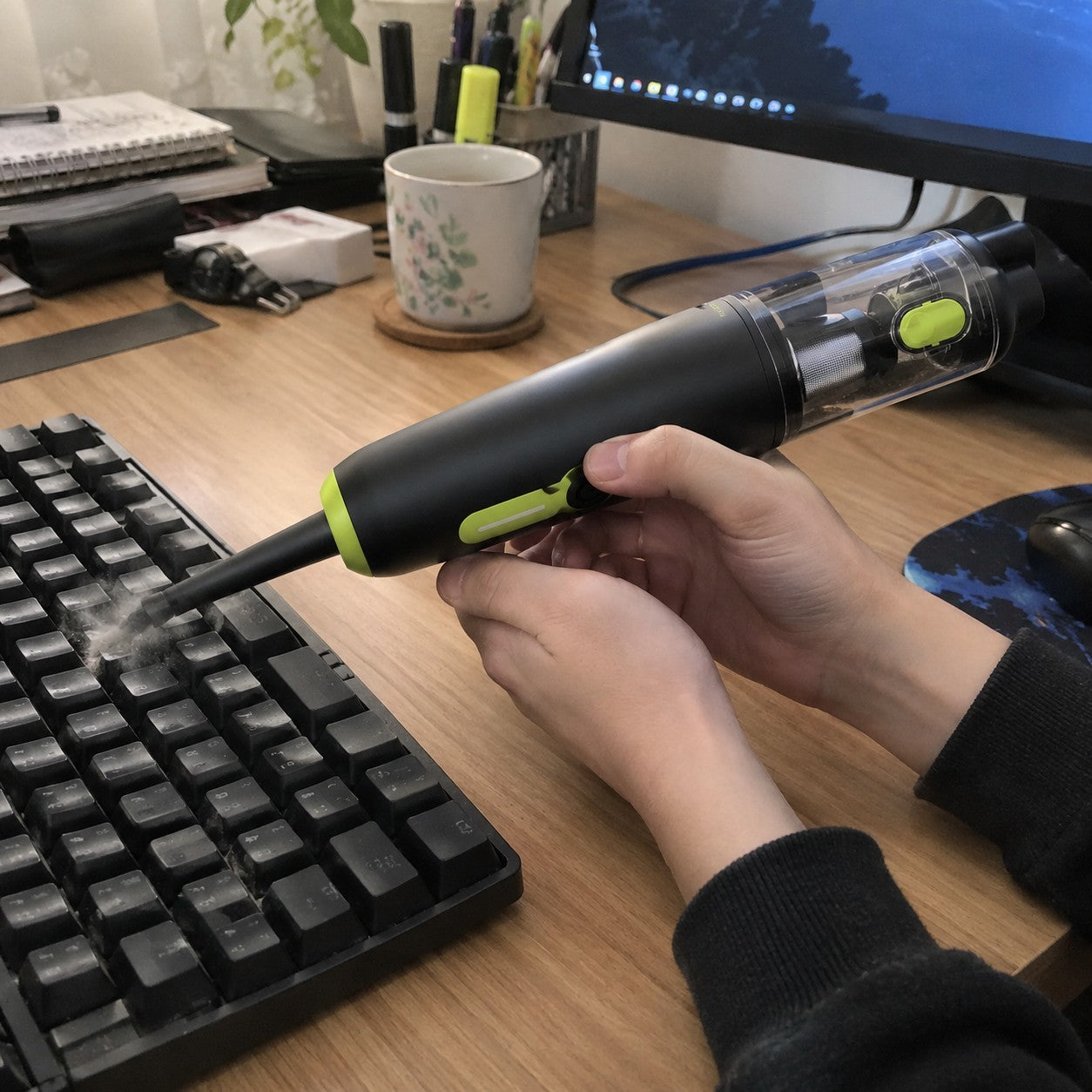 Hands blowing dust out of a keyboard gap on a desk