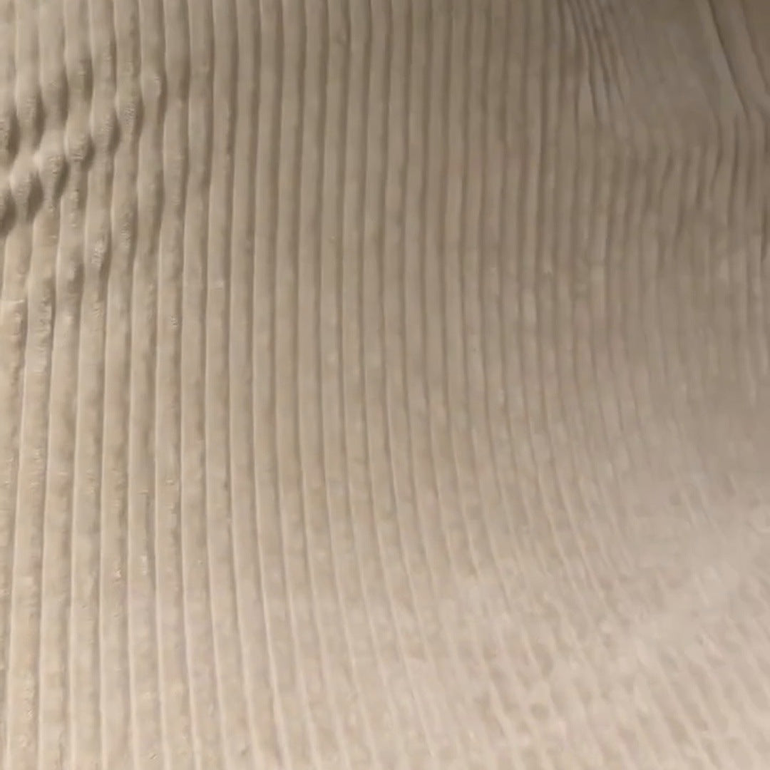 The Cream raised ribbed stripes in clean lines across a couch cushion with natural folds, headline words drawn at the top right