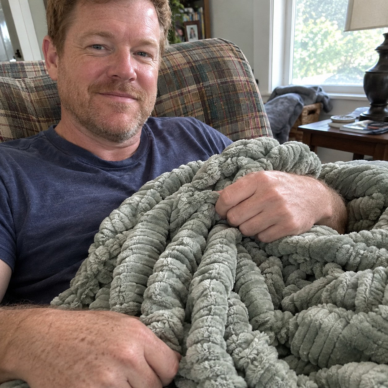 Owen selfie on the checked armchair holding the Sage ribbed plush blanket