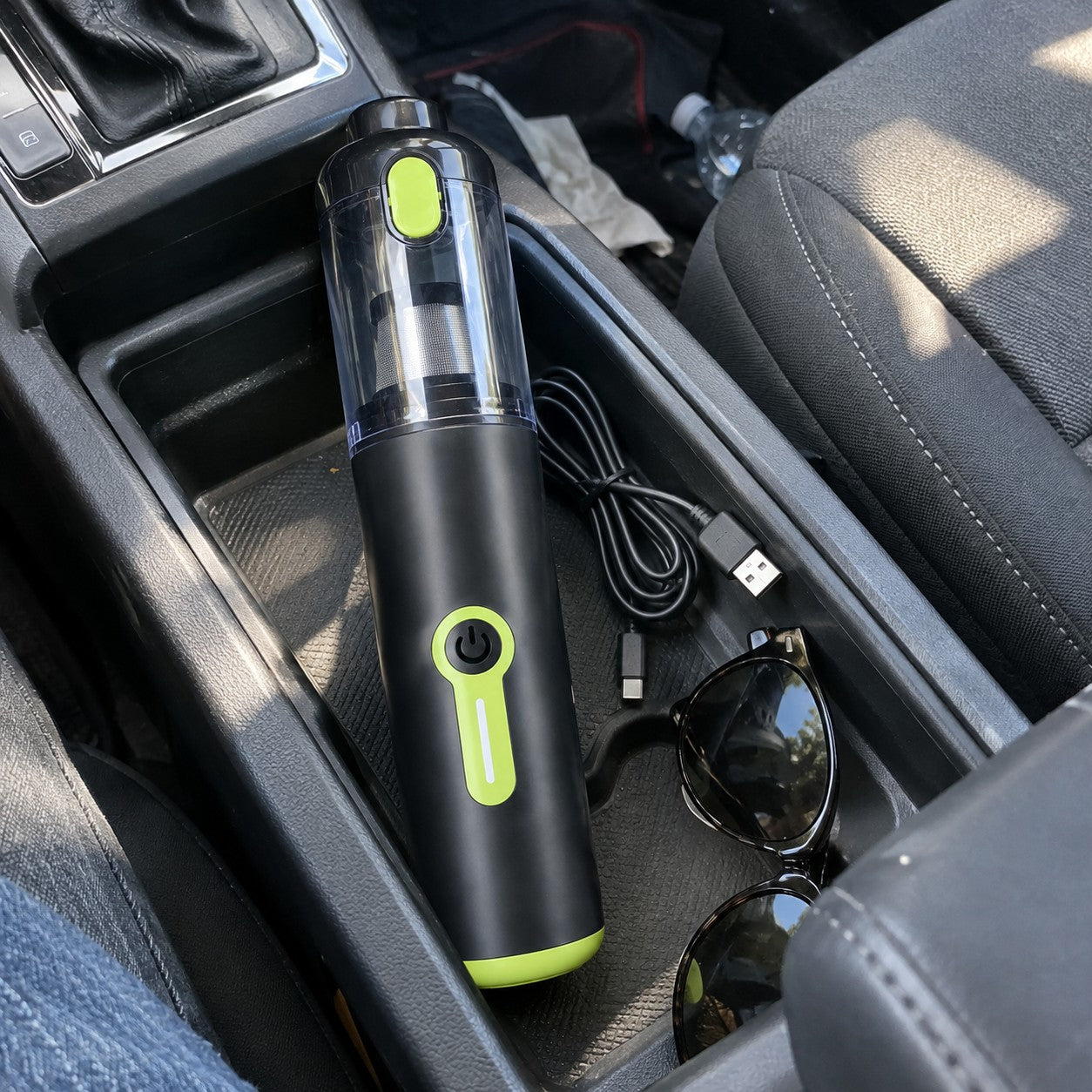 Black and lime cylindrical vacuum stored in a console tray with cable and sunglasses