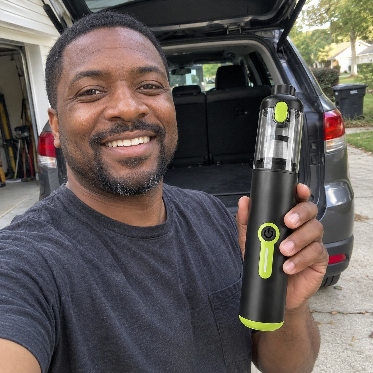 Black adult man holds the correct black and lime cylindrical vacuum beside an SUV