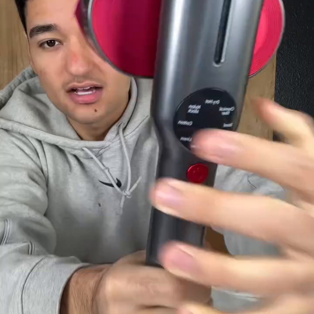 A man in a gray hoodie holds the handheld close to the camera with its magenta head turned outward