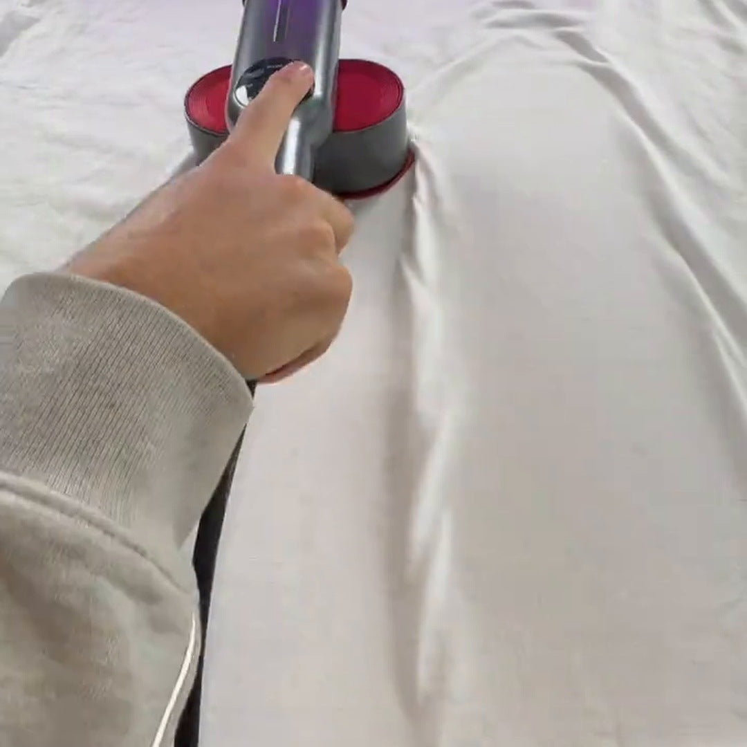 Actual steamer held over white fabric on an ironing surface, cord visible