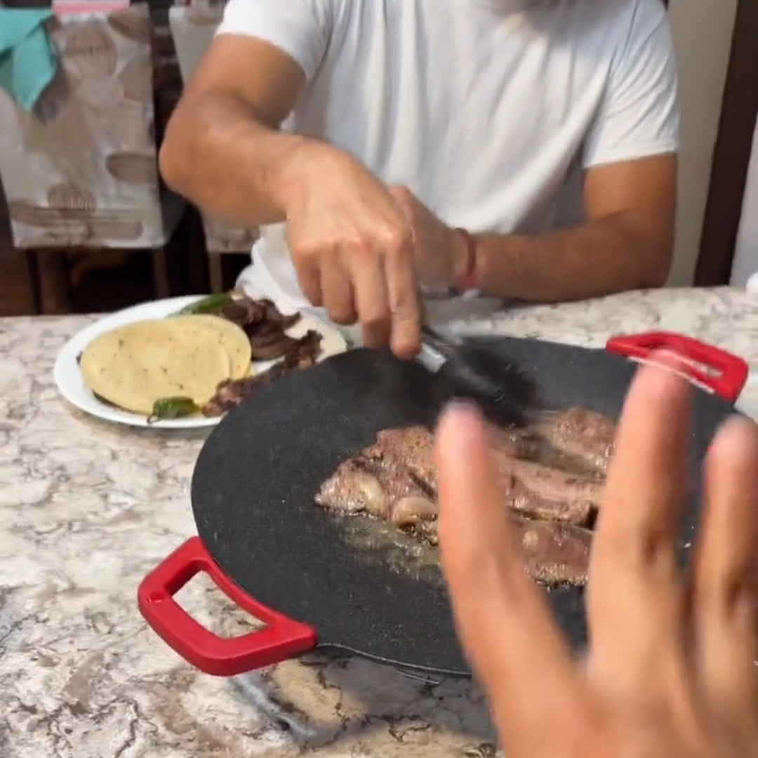 Real cook using tongs on steak on the round red-handled grill