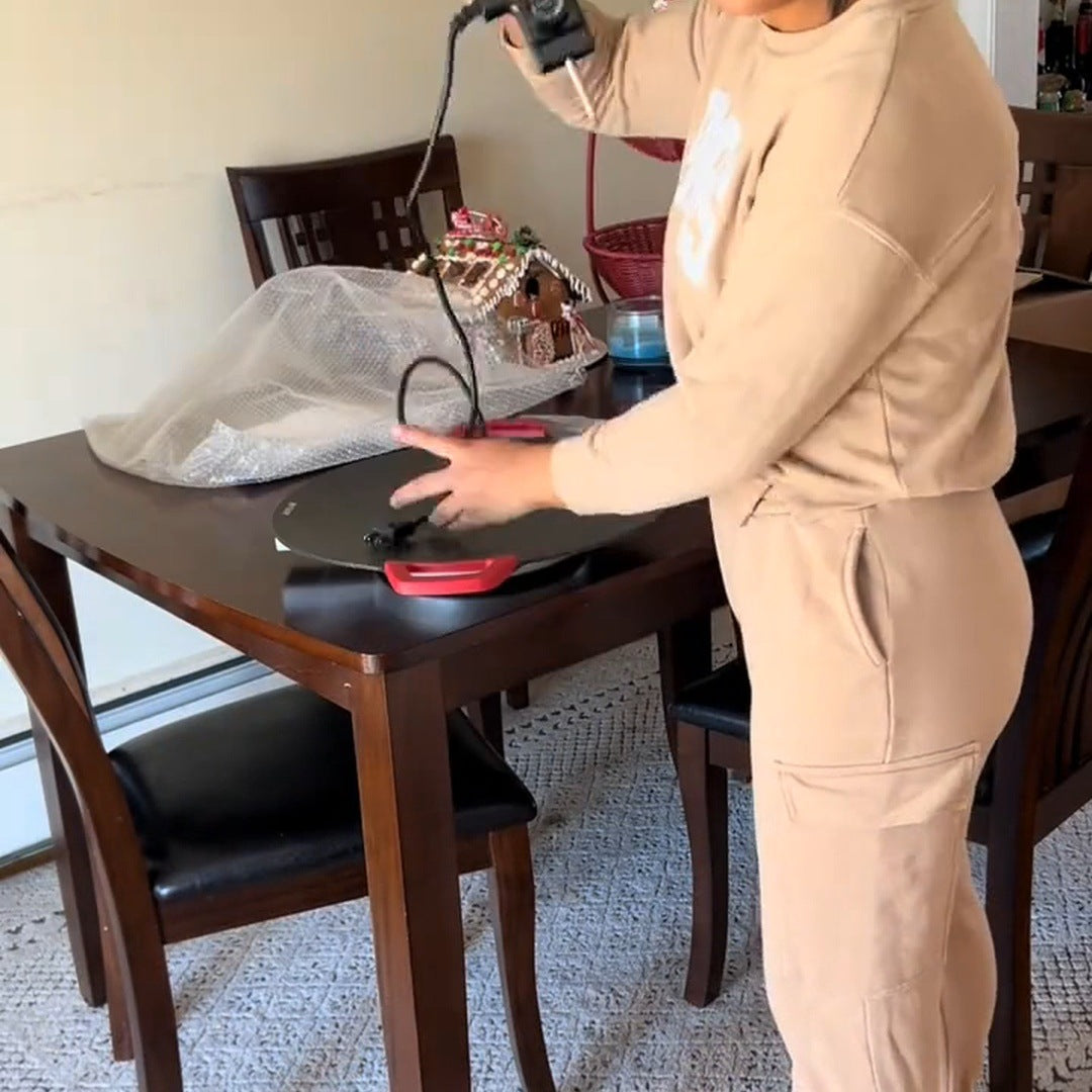 Real creator in a tan outfit holding the corded controller over the red-handled grill on a dining table