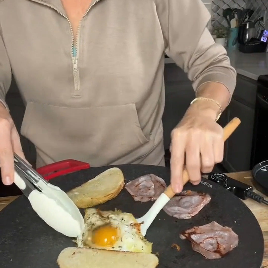 Real cook moving a fried egg toward bread with a spatula on the round grill
