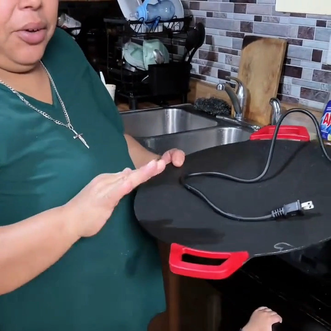 Real creator in teal holds the unplugged round grill with its cord and plug resting across the cooking surface