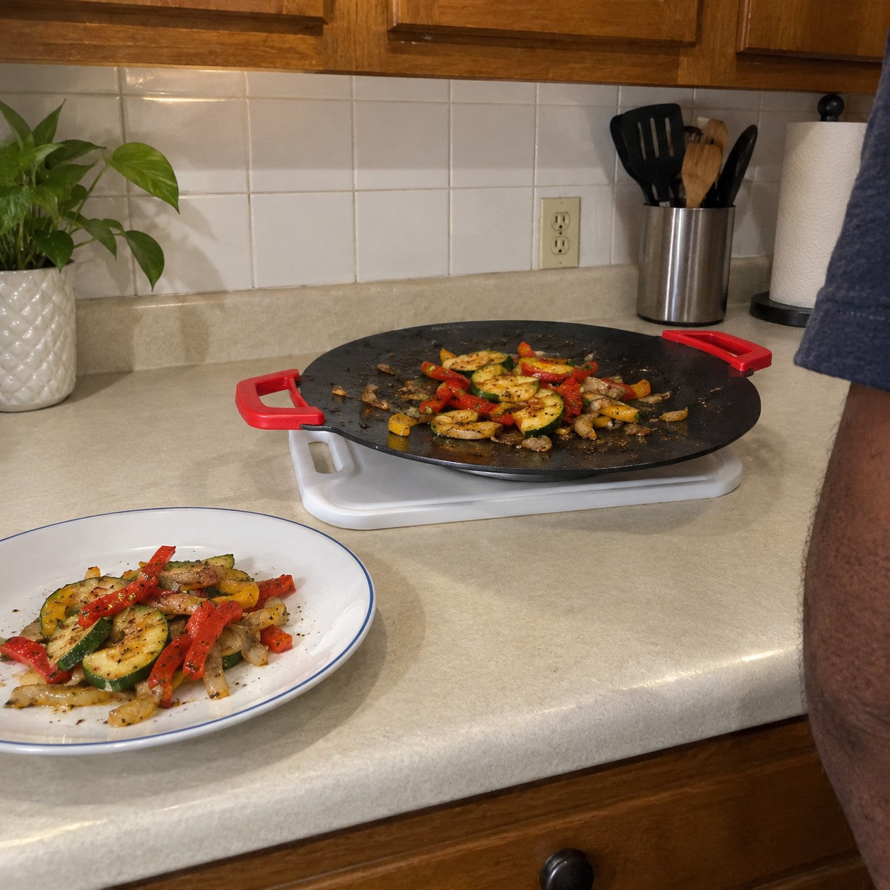Vegetables on the red-handled grill and a finished plate beside it in Marcus J. kitchen