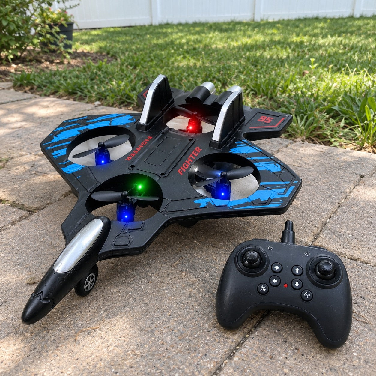 The jet and remote on a lawn by a patio, red wing markings visible