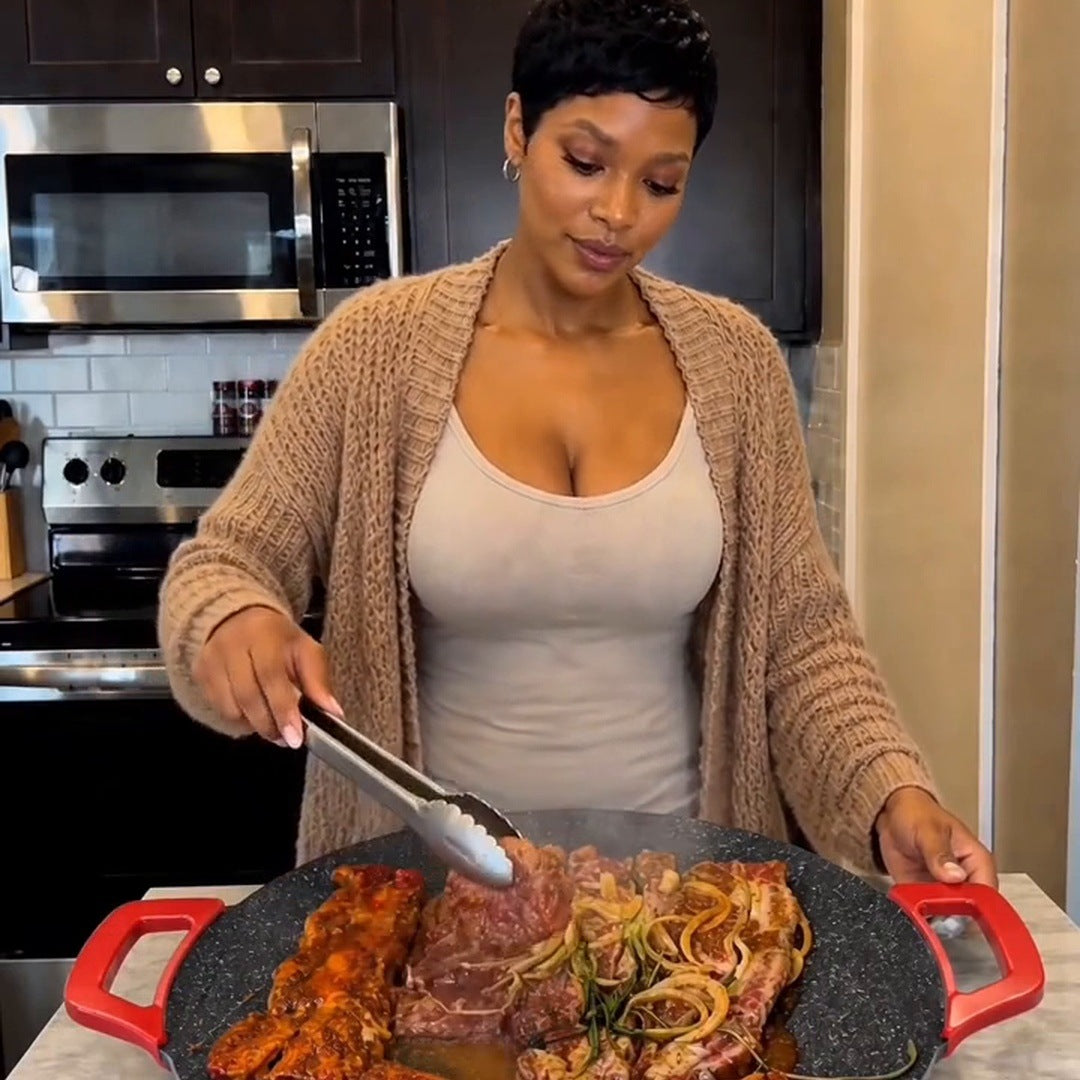 A real woman uses tongs over chicken, steak and onions on the large round speckled grill