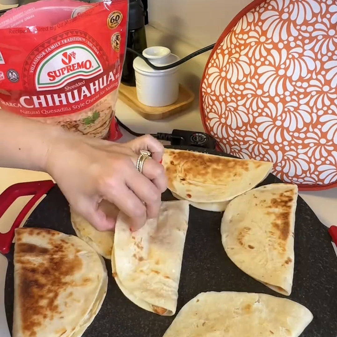 Real footage frame of a hand lifting a browned quesadilla on the speckled grill
