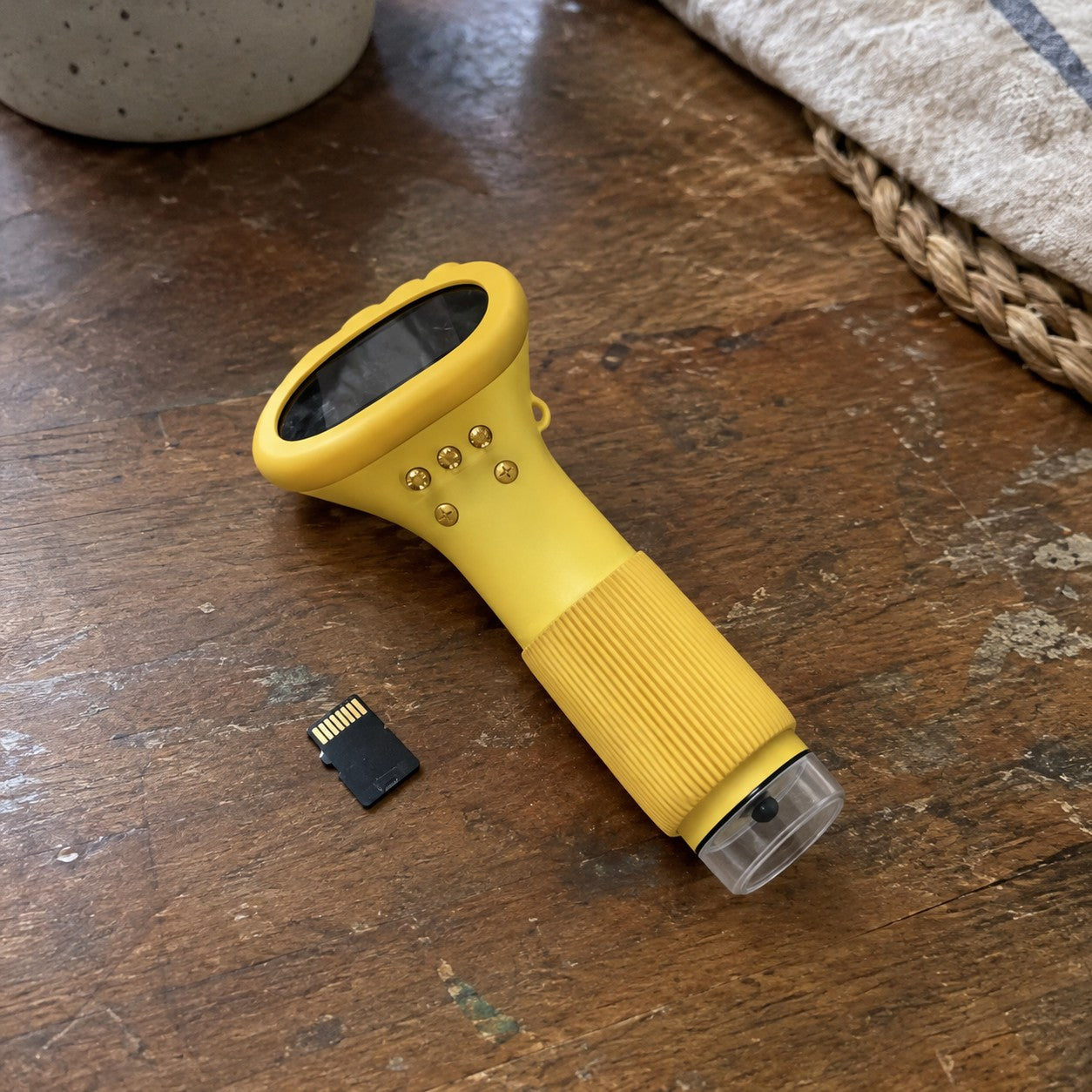 Yellow microscope and one microSD card lie on a worn wooden table