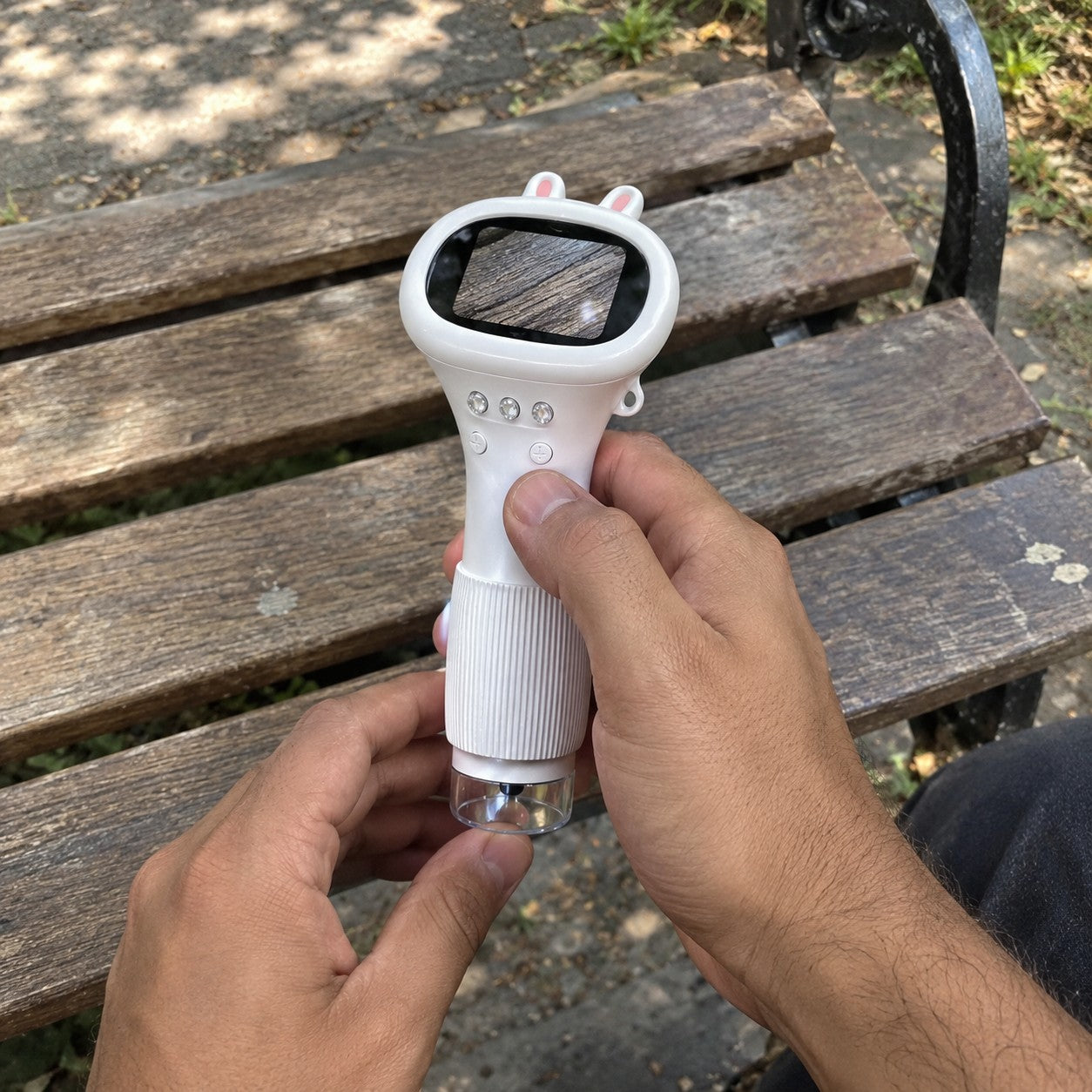 Hands hold the white bunny scope over a worn park bench