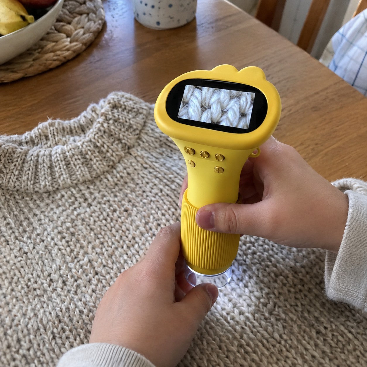 Child holding yellow scope over a knit sweater
