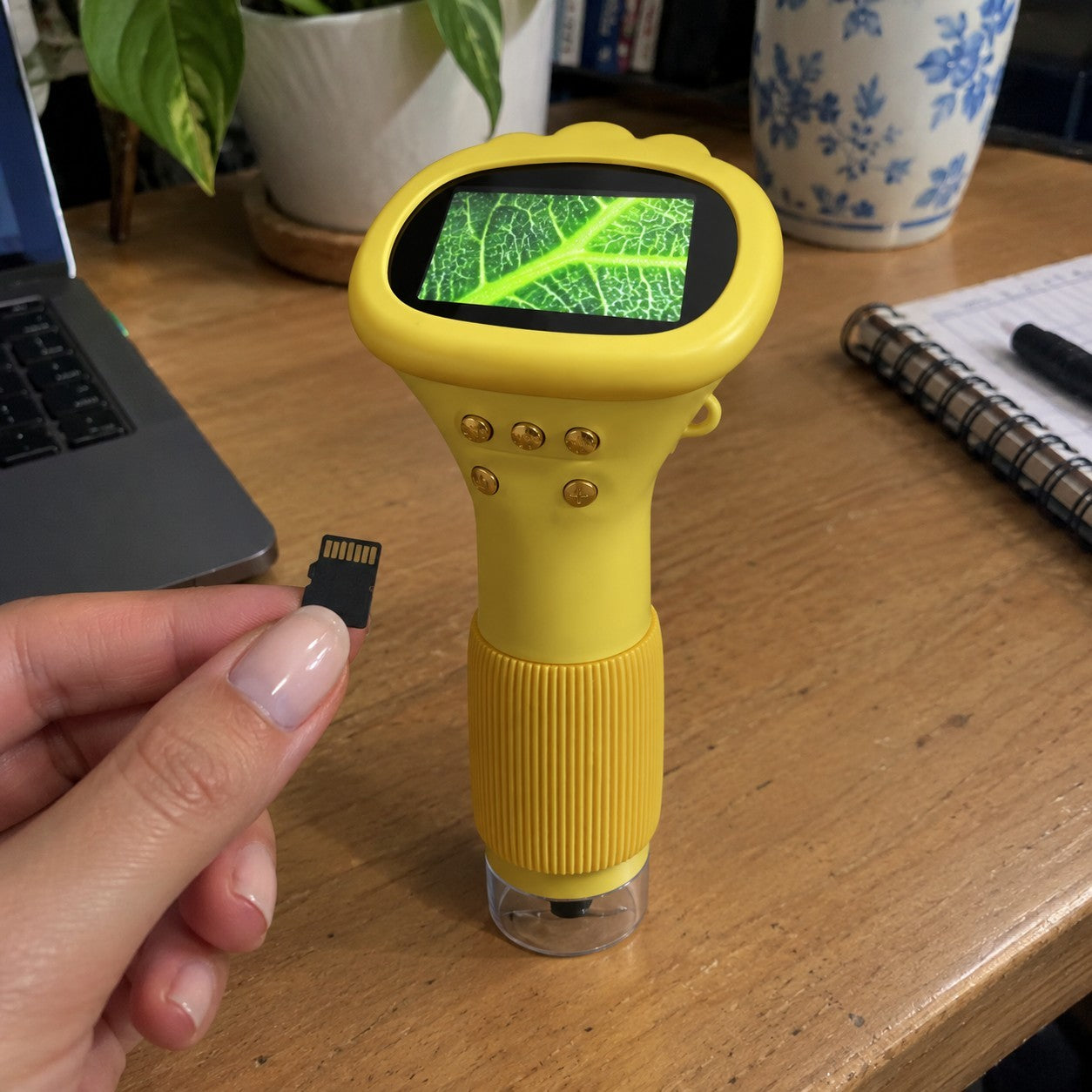 Hand placing a microSD card beside yellow scope